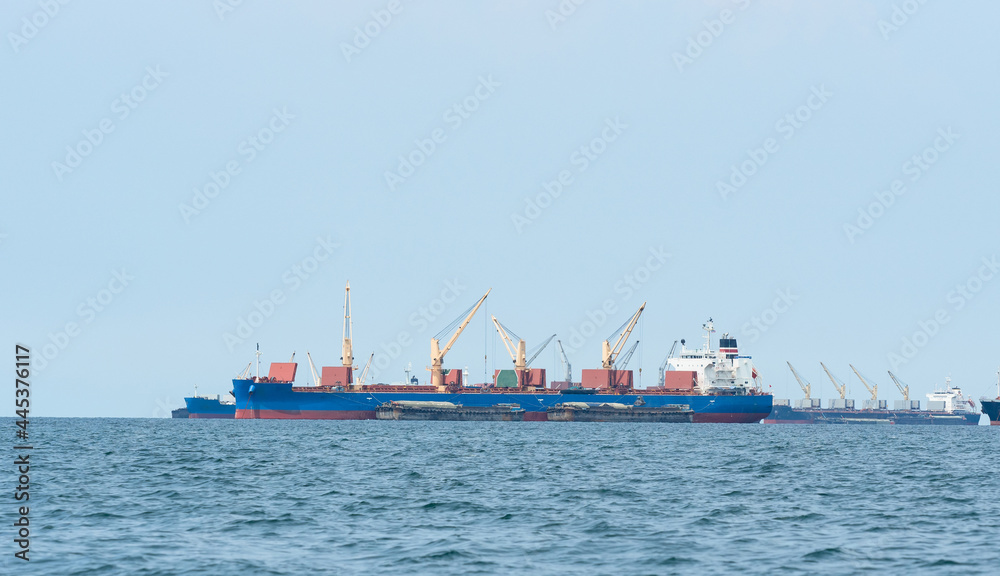 Large cargo ship red color with big crane in the blue ocean and blue sky landscape,Industrial boat in the sea logistic concept