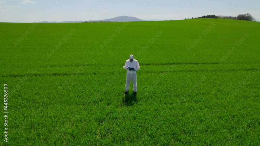 Scientist biologist in a gas mask and protective suit examines the field with the help of modern technologies. Scientist biologist in a gas mask and protective suit examines the field with the help of modern technologies.