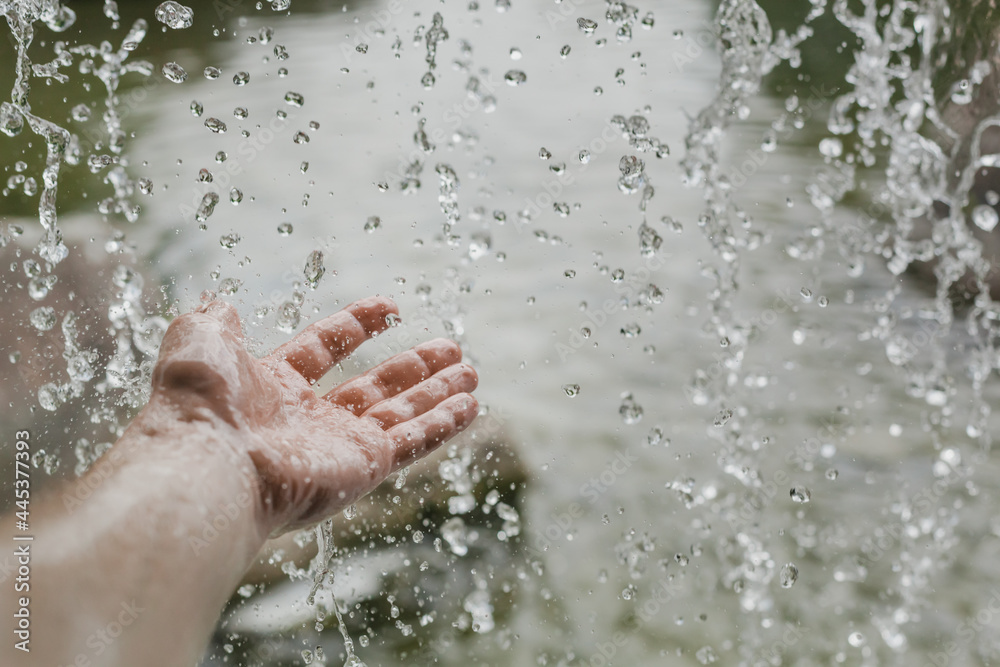 Fototapeta premium splashing water falling on a man's hand from a waterfall