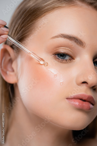 close up of pretty woman applying vitamin c serum with pipette
