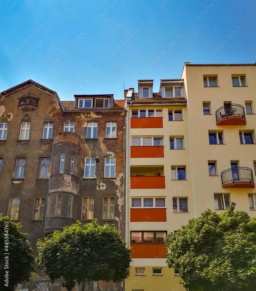 Fototapeta premium Looking up to city contrast of old tenement house and modern block of flats