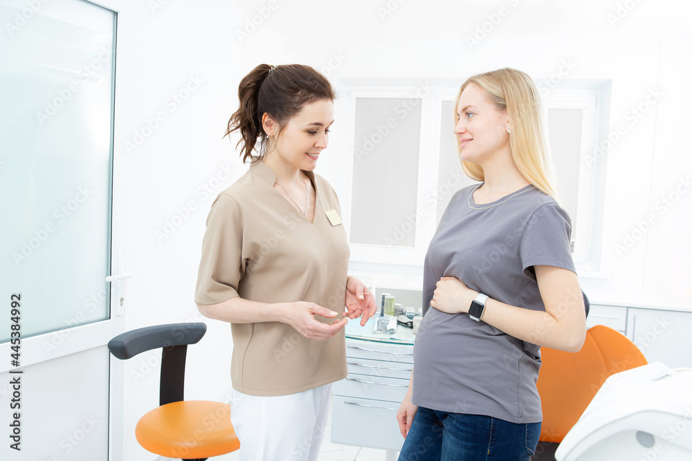 positive pregnant woman in dentist office, consultation with young woman dentist. dental treatment for pregnant women positive pregnant woman in dentist office, consultation with young woman dentist. dental treatment for pregnant women