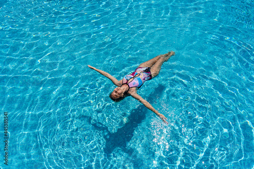 Young woman lies on a water surface in the crystal pool © Anton Tolmachov