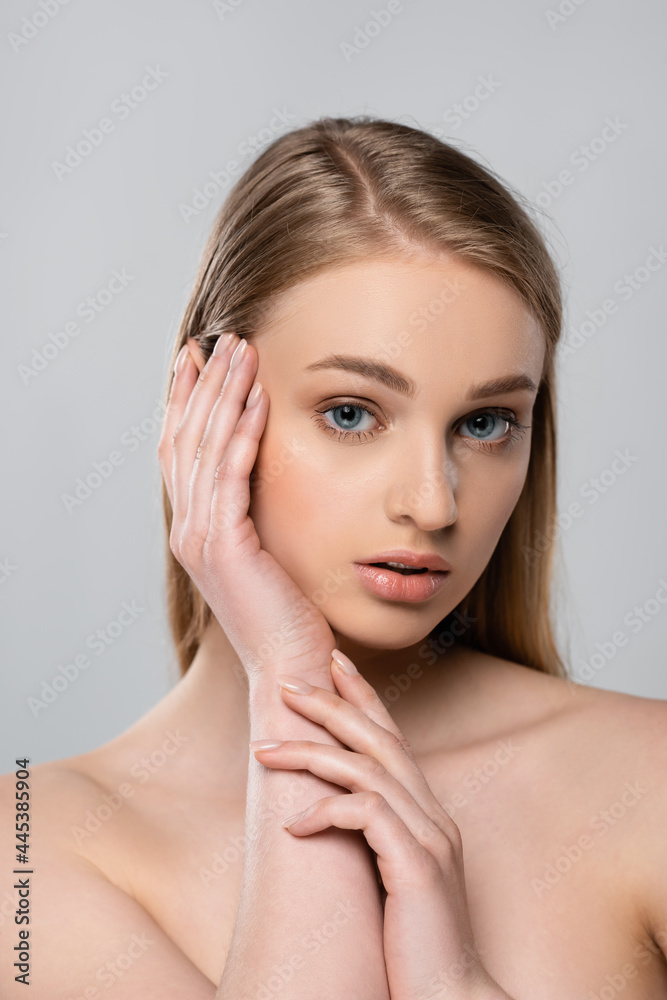 young woman with bare shoulders touching face isolated on grey young woman with bare shoulders touching face isolated on grey