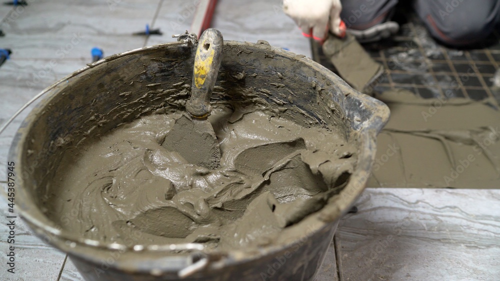 Fototapeta premium A device for mixing ceramic tile adhesive. Glue bucket. Mixing glue in a bucket. A worker mixes tile adhesive in a bucket.