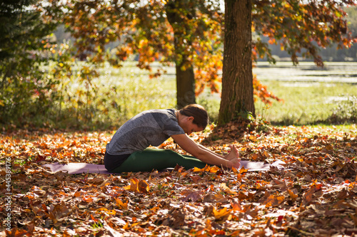 Woman doing yoga in the park in fall