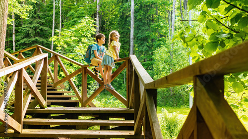 Children observe wild animals in the reserve sitting on the railing of the equipped tourist route. Family travel vacation concept. Kids travel to family camping. Atmospheric photo for travel brochures © nieriss