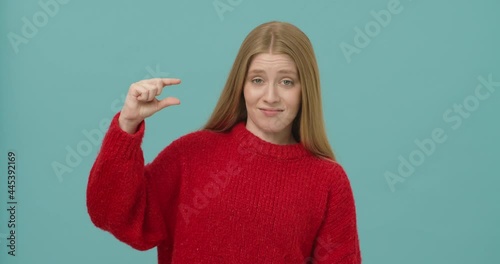 Young woman with long blond hair mocking over small size showing it with fingers.