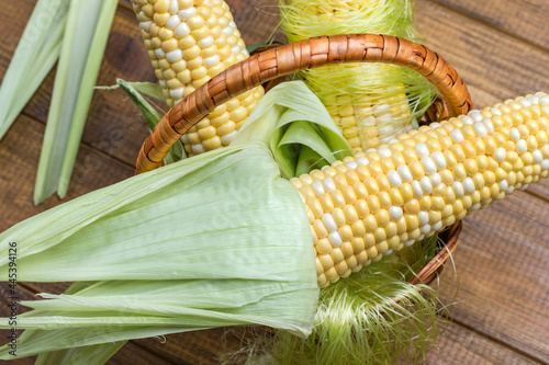Raw corn with leaves in wicker basket