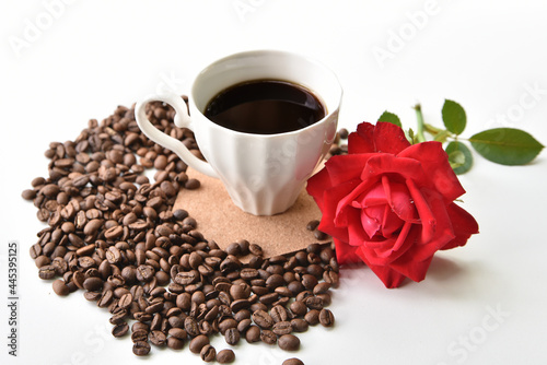 Coffee, red rose and scattered coffee beans on a white background