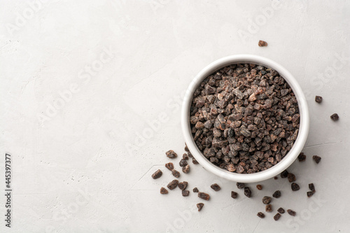 Himalayan or Indian black salt in ceramic bowl on grey concrete background