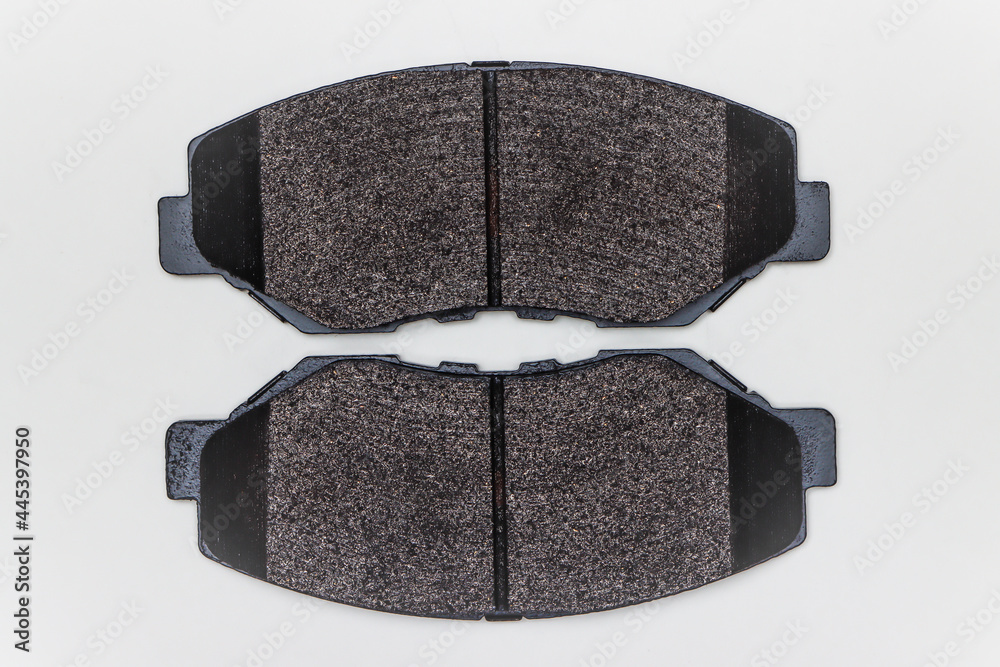 Two brake pads on a flat surface. Set of spare parts for car brake repair. Details on white