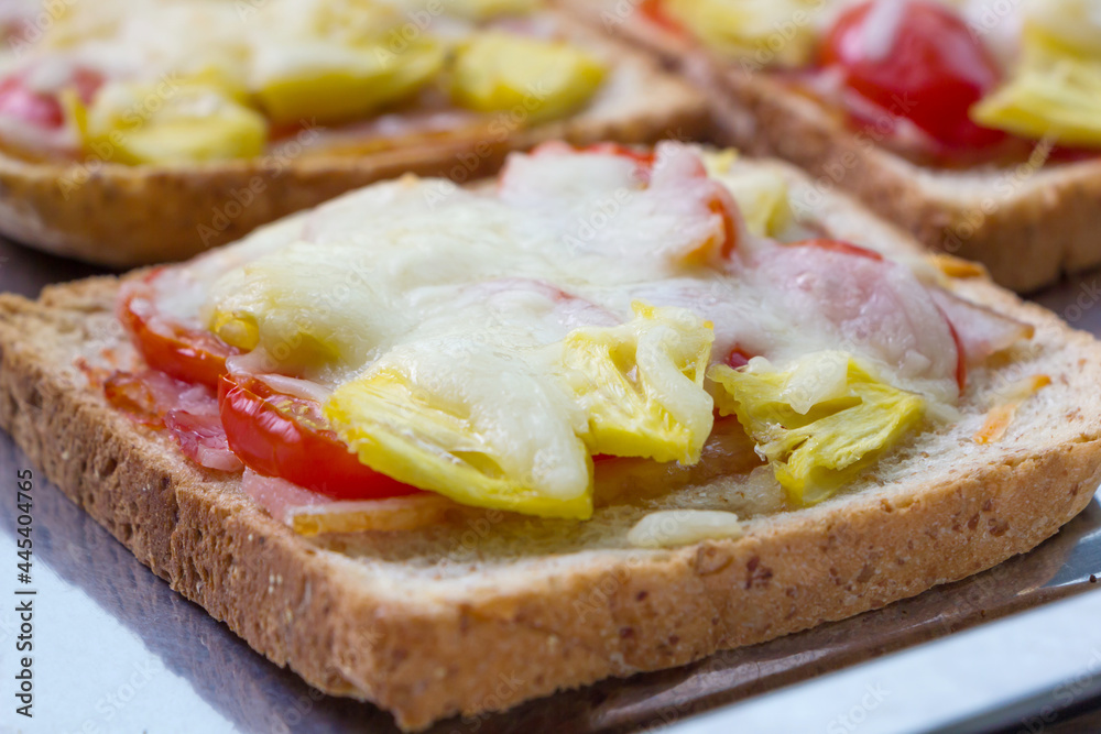 Pizza toasted bread, cheese toasted bread with tomato and pineapple. close up