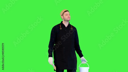 Renovation ervice worker painter walk with jar of paint and painting brush looking around on walls on a Green Screen, Chroma Key. photo