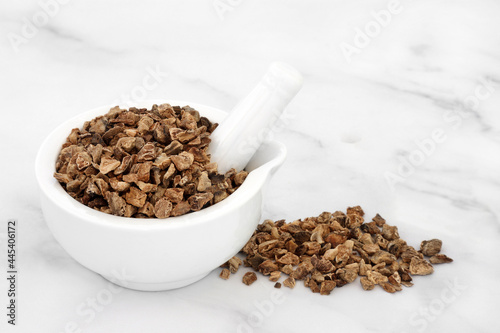 Devils claw root in a mortar with pestle used in herbal medicine to treat arteriosclerosis, arthritis, gout, fibromyalgia, tendonitis, heartburn, migraine, muscle pain and fever. On marble background. photo
