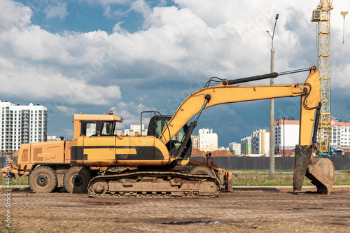 The excavator and the grader stand side by side against the blue sky. Heavy construction earthmoving equipment. Construction of roads and underground communications. Construction industry.