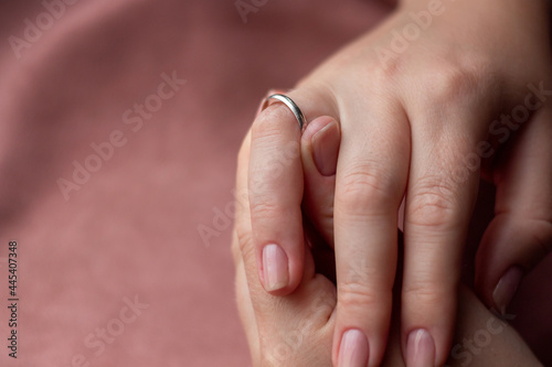 shows a large size wedding ring on a finger with a place for text on a pink background photo