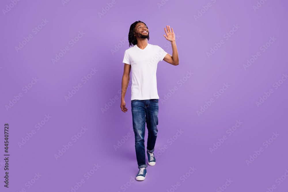 Full body photo of charming happy dark skin dreamy man look empty space wave walk isolated on violet color background