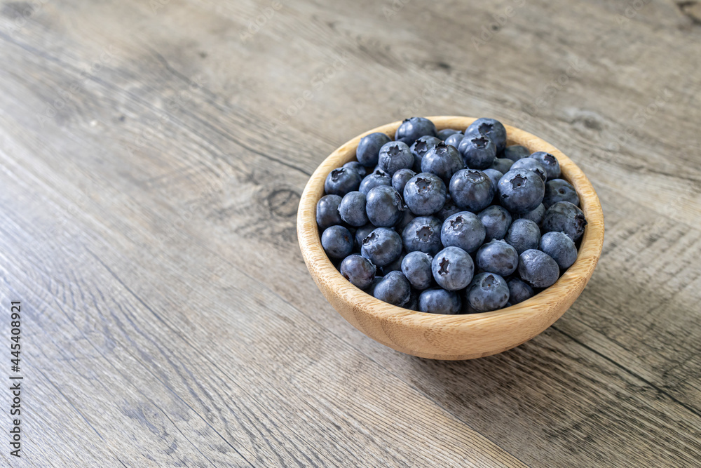 Fresh blueberries in a bamboo bowl isolated on a wooden table. Healthy diet high in antioxidants and fresh fruit healthy eating concept. Fresh blueberries in a bamboo bowl isolated on a wooden table. Healthy diet high in antioxidants and fresh fruit healthy eating concept.
