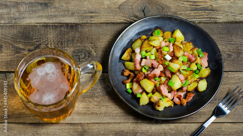 Roasted potatos with pork on the wooden background with cup of beer.