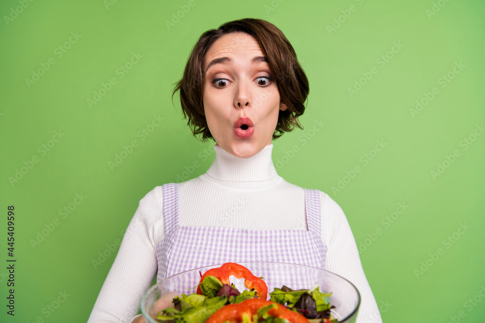 Photo of young girl amazed shocked look salad dieting weight loss vegetarian isolated over green color background Photo of young girl amazed shocked look salad dieting weight loss vegetarian isolated over green color background