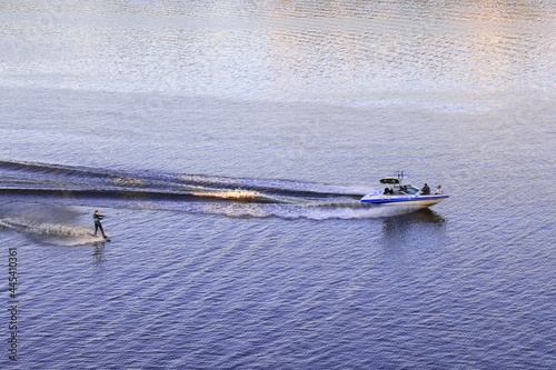 Foam waves behind a boat with a water skier on the river at sunset, July 2021 photo