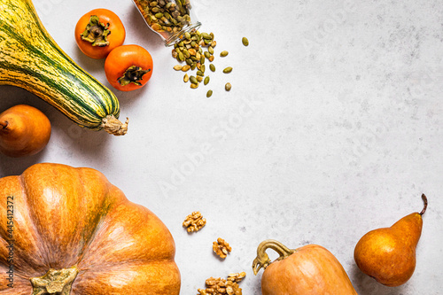Autumnal background with pumpkins, pears, walnuts, pumpkin seeds, persimmons and copy space photo