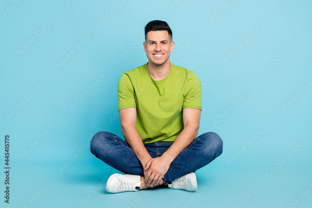 Full length body size photo man casual clothes sitting down smiling isolated pastel blue color background Full length body size photo man casual clothes sitting down smiling isolated pastel blue color background
