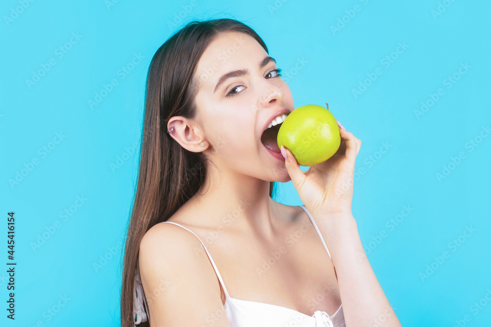 Woman eat green apple. Portrait of young beautiful happy smiling woman with green apples. Healthy diet food. Stomatology concept. Woman with perfect smile holding apple, blue background Woman eat green apple. Portrait of young beautiful happy smiling woman with green apples. Healthy diet food. Stomatology concept. Woman with perfect smile holding apple, blue background