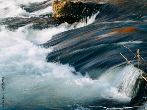 the flow of a stormy river over rocks, clear blue water
