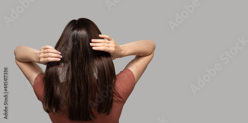 Banner with turned back girl touching her hair on light background