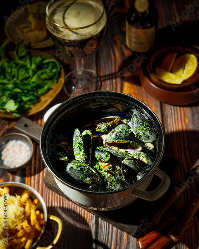 Mussels in a pan, french fries, bread and beer on wooden rustic background