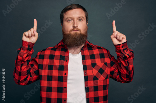 Fotografija Skeptical unsure handsome macho man in red checkered shirt, pointing up and look