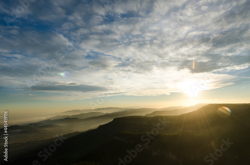 imagen de la puesta de sol de lo alto de una montaña con el cielo nublado y la humedad entre las montañas 
