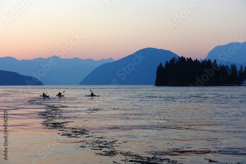 A group of kayakers kayaking on the open calm still ocean during sunset on a beautiful calm evening on the Sunshine coast, in British Columbia, Canada photo