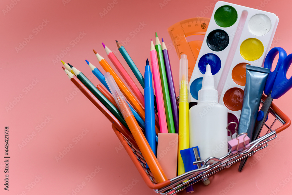 Obraz premium School supplies in a shopping basket on a pink background. Preparing for school, buying office supplies. Back to school.