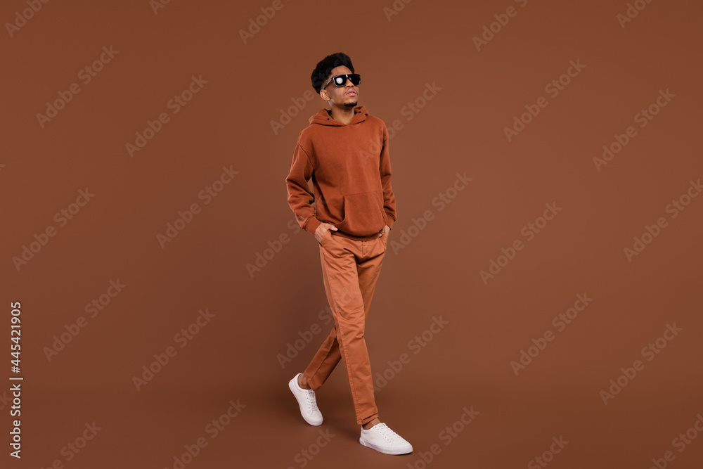 Full size profile side photo of young african man serious confident go walk step hands in pocket isolated over brown color background Full size profile side photo of young african man serious confident go walk step hands in pocket isolated over brown color background