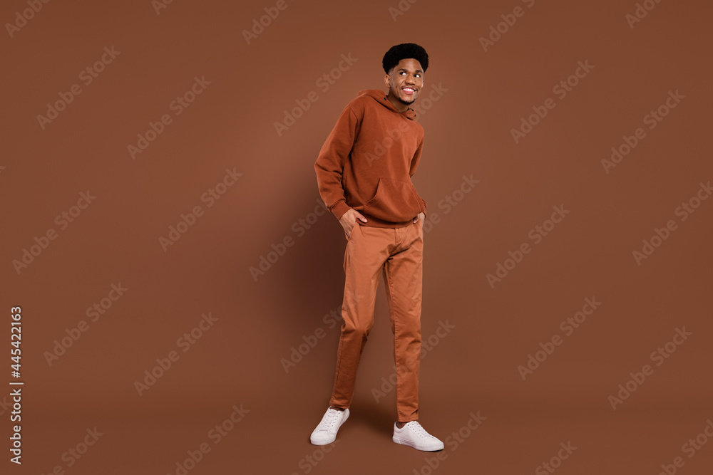 Full body photo of funny short hairdo young guy look empty space dress sportswear trousers sneakers isolated on brown color background Full body photo of funny short hairdo young guy look empty space dress sportswear trousers sneakers isolated on brown color background