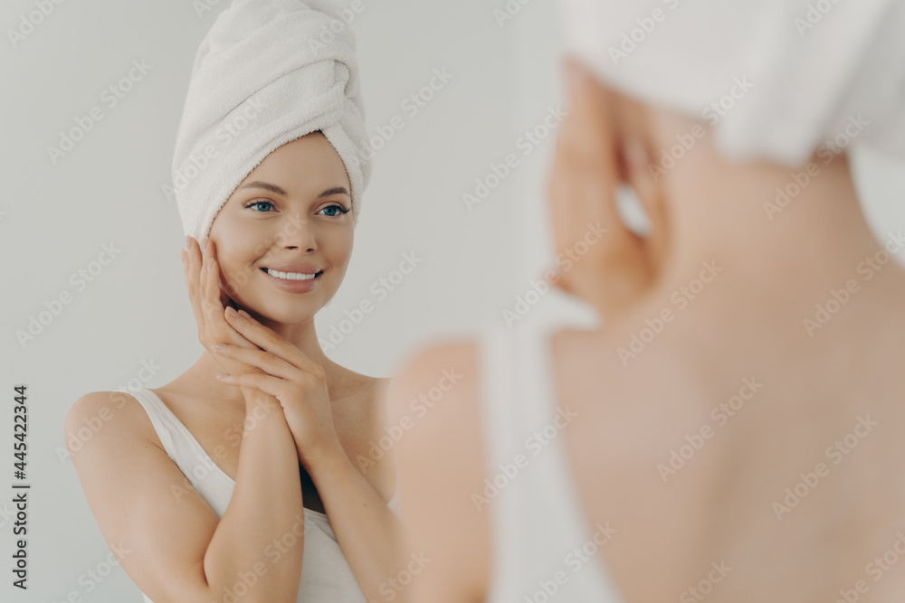 Beautiful happy woman after applying make up looking in mirror and smiling while standing in bathroom Beautiful happy woman after applying make up looking in mirror and smiling while standing in bathroom