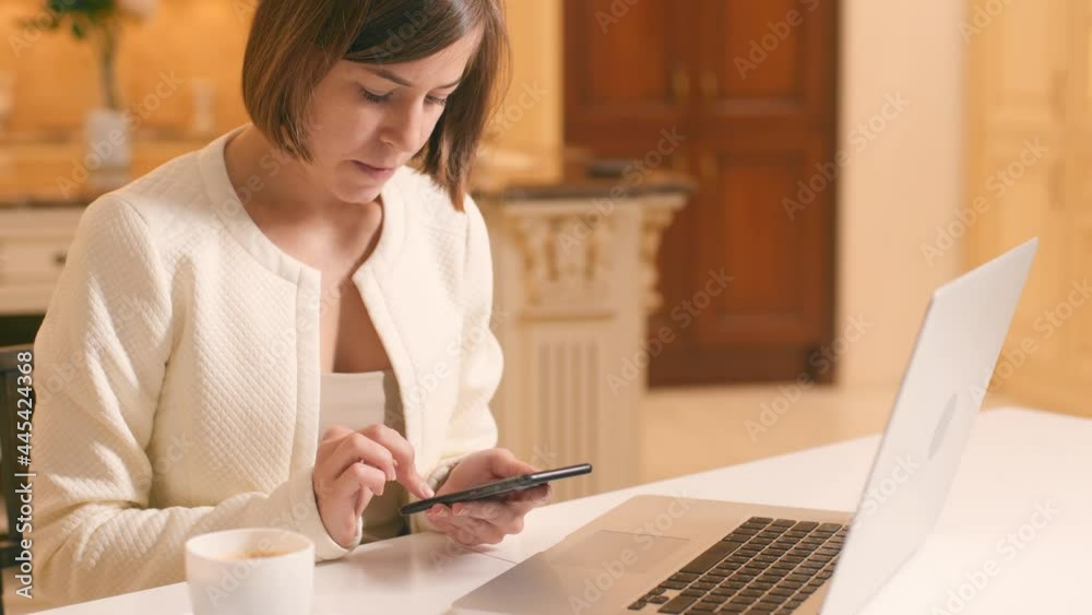 Business Woman Uses Smartphone For Communicates With Clients at Home Office Workplace at Modern Kitchen. Female Freelancer Chatting On Mobile Phone. Girl Typing Message On Phone Chatting With Friends.