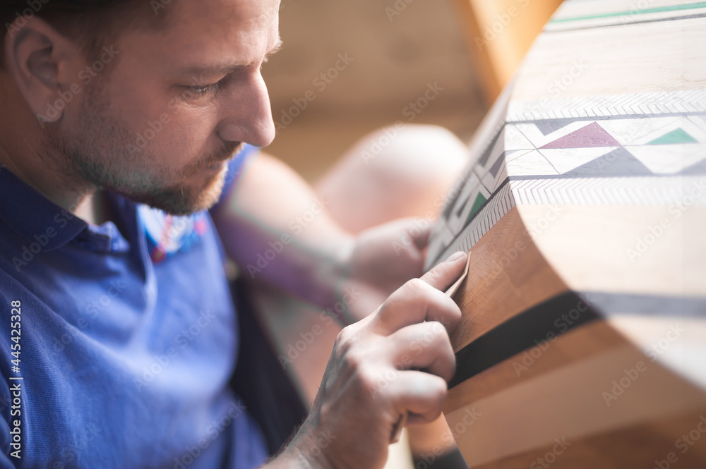 Obraz premium Master in the workshop. Man polishing wood with sandpaper. Carpentry concept with wood