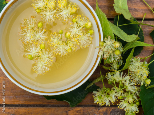 Cup of green tea and linden on wooden background, useful linden flowers folk medicine concept