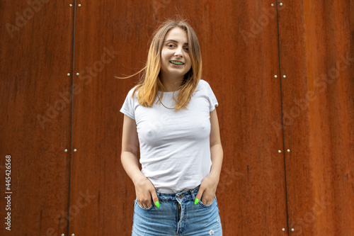 Portrait of a young woman with dental braces on teeth. On a rusty wall background. photo