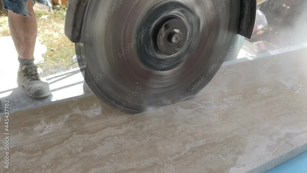Man cuts a marble slab with the rotary saw in slowmotion Man cuts a marble slab with the rotary saw in slowmotion
