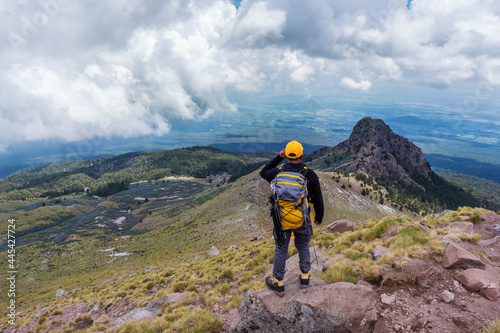 A hiker with a backpack standing on the top of the mountain