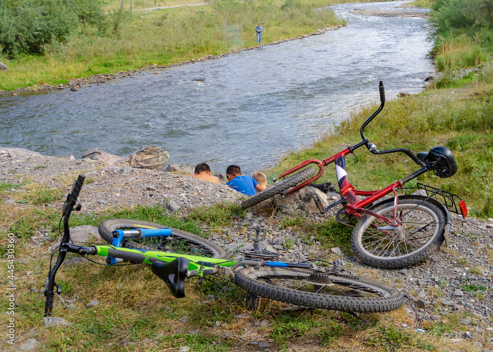 The children have put their bikes down and are doing something on the riverbank The children have put their bikes down and are doing something on the riverbank