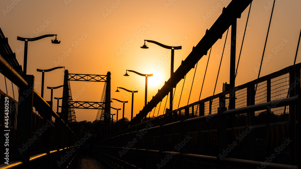 Fototapeta premium Orange sunset over the Sita Bridge in Rishikesh, Uttarakhand, India
