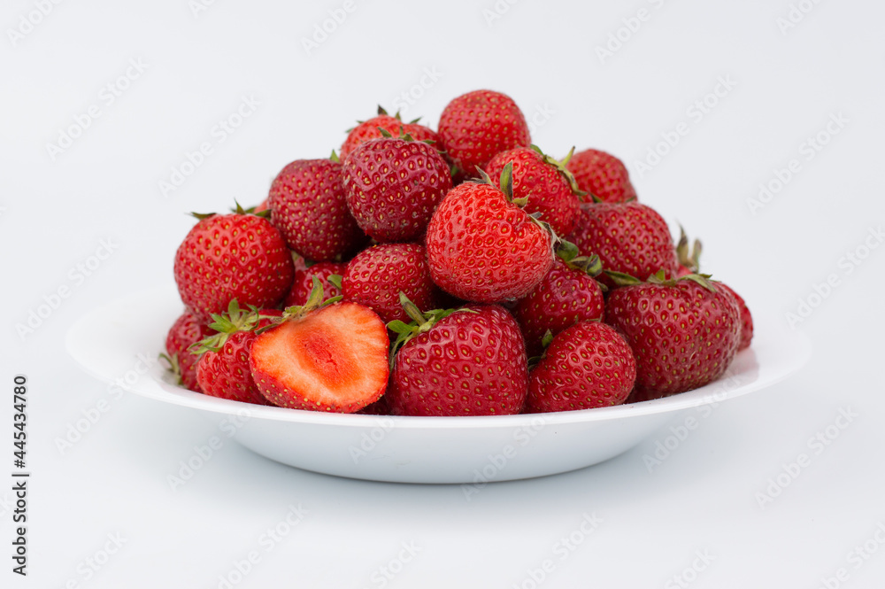 On a white background, a white plate with ripe strawberries. On a white background, a white plate with ripe strawberries.