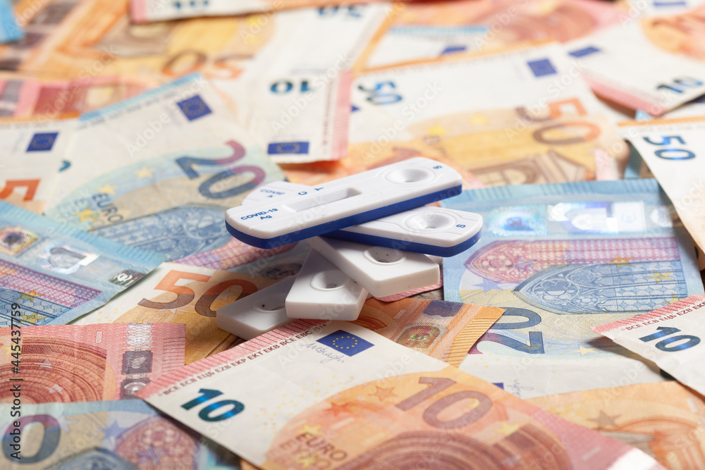 Rapid diagnostic tests lying on top of pile of money symbolizing making business thanks to COVID-19 pandemic Rapid diagnostic tests lying on top of pile of money symbolizing making business thanks to COVID-19 pandemic