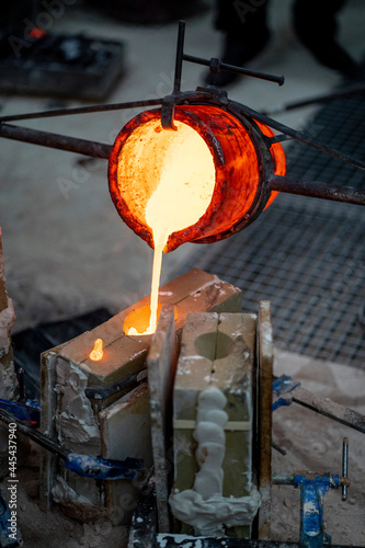 Furnace container pouring melted bronze at foundry photo